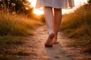 Donna che cammina a piedi scalzi nella natura al tramonto, simbolo di equilibrio tra lavoro e vita