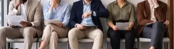 Persone sedute in sala d’attesa prima di un colloquio di lavoro, ognuna con un atteggiamento diverso