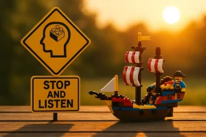 Cartello giallo “Stop and Listen” accanto a una nave LEGO illuminata dal tramonto, simbolo della pausa necessaria per ascoltare e ritrovare chiarezza.
